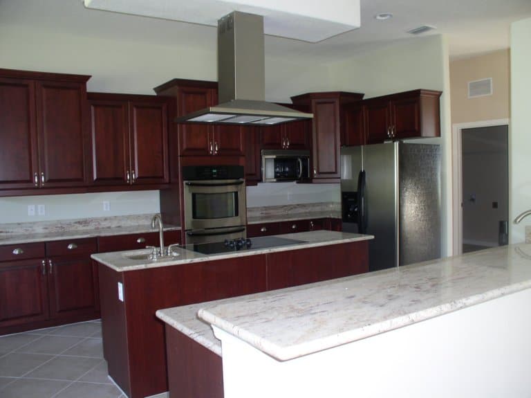 red wooden kitchen cabinets and kitchen island with whitemarble countertops