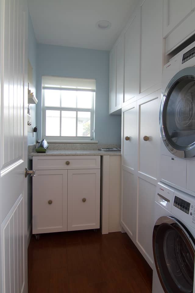 laundry room with white cabinets and stacked washer and dryer